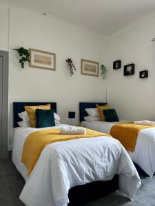a bedroom with two beds with yellow and white sheets at 4 Bed House! 10%OFF! Groups, Contractors! 9 Guests - Garden - Free On street Parking in Cardiff