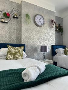 a bedroom with two beds and a clock on the wall at 4 Bed House! 10%OFF! Groups, Contractors! 9 Guests - Garden - Free On street Parking in Cardiff