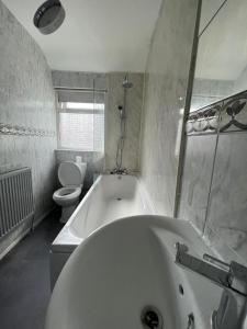 a white bathroom with a tub and a toilet at 4 Bed House! 10%OFF! Groups, Contractors! 9 Guests - Garden - Free On street Parking in Cardiff