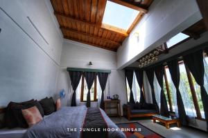 a bedroom with a bed in a room with windows at The Jungle Hook Binsar in Almora