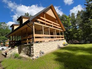 a home with a stone wall and a house at Domek Serce Lasu in Hutki