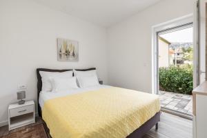een witte slaapkamer met een bed en een glazen schuifdeur bij Apartments Villa Salona Sky in Solin