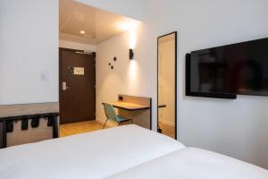 um quarto com uma cama, uma secretária e uma televisão em B&B HOTEL Mechelen em Mechelen