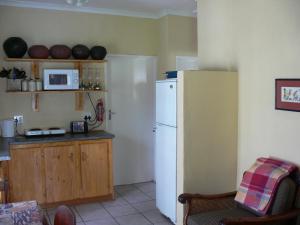 uma cozinha com um frigorífico branco e um micro-ondas em Aspen Guest House em Clarens