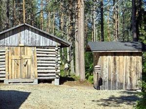 una cabaña de madera y un cobertizo en el bosque en Ferienhaus in Kemijärvi mit Offenem Kamin, en Vuostimo