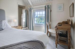 a bedroom with a bed and a desk and a window at Dollars Cottage - 4 Bedroom Cottage - Llangennith in Llangennith
