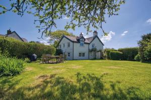 a white house with a picnic table in the yard at Dollars Cottage - 4 Bedroom Cottage - Llangennith in Llangennith