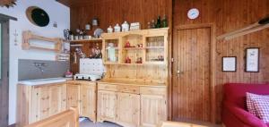 une cuisine avec des placards en bois et un canapé rouge dans l'établissement Charming Mountain Hut on Grigna Mountain - Como Lake, à Pasturo