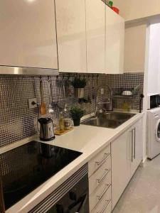 una cucina bianca con lavandino e lavastoviglie di An elegant & cozy apartment ad Amadora