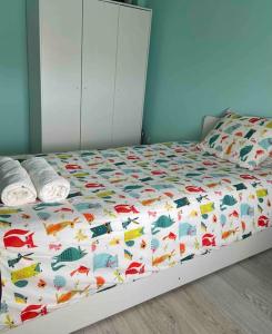a bed with a colorful comforter with a bedskirtspectspectspectspects at An elegant & cozy apartment in Amadora