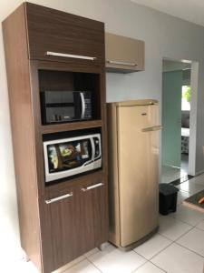 a kitchen with a microwave and a refrigerator at Casa praia de Itapirubá a 100 metros do mar in Imbituba