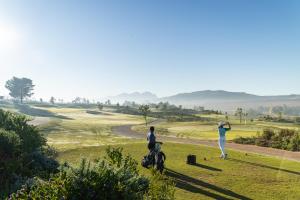 a group of people standing on a golf course at The Homestead at Hazendal Wine Estate by NEWMARK in Stellenbosch