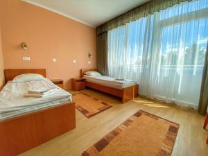 a bedroom with two beds and a large window at Arkánum Hotel in Balatonmáriafürdő