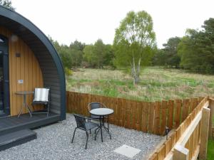 a patio with a table and chairs and a fence at Tanleys - Skye Pod in Grantown on Spey