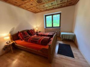 a bedroom with a bed with red sheets and a window at Schnitzer-Stüble in Missen-Wilhams