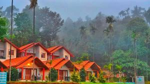 a row of houses with palm trees in the background at Hill Crest Resort - Coorg in Madikeri