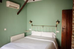 Bett in einem Zimmer mit grünen Wänden in der Unterkunft CASA RURAL La Moranta in Herguijuela