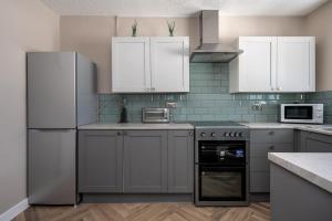 una cocina con electrodomésticos blancos y armarios blancos en Charming 2-Bed Home in Neath en Skewen