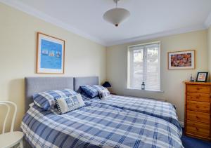 een slaapkamer met een blauw en wit bed en een raam bij Flat 3 Durlston Court in Swanage