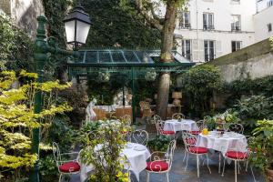 a patio with tables and chairs in a garden at Hôtel Des Marronniers in Paris