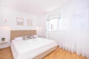 a white bedroom with a bed and a window at Flying Bridge in Podstrana