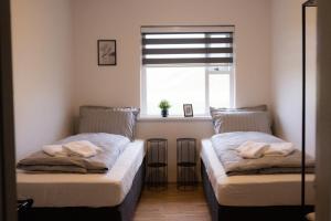 two beds in a room with a window at Guesthouse Helluland in Þingeyjarsveit