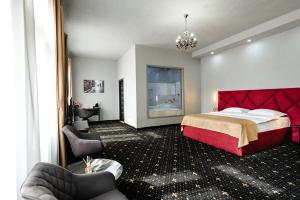 a hotel room with a large bed and chairs at Palace Bulevard Inn in Cluj-Napoca