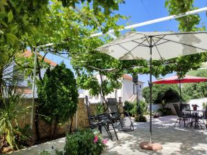 eine Terrasse mit Sonnenschirm und Tisch und Stühlen in der Unterkunft Villa Grande Vista - Lovely Apartment with Private spacious lush mediterranean patio and Sea view in Trogir