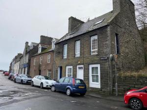 uma fila de carros estacionados em frente a um edifício de tijolos em Modern Apartment - Wick Harbour em Wick