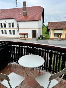 un tavolo bianco e 2 sedie sul balcone di Karla’s House a Dobje pri Planini