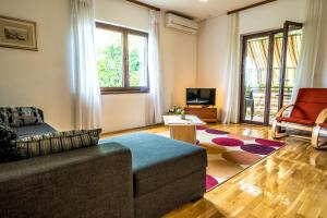 uma sala de estar com um sofá e uma televisão em Apartmani Rosa em Turanj
