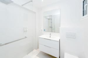 Baño blanco con lavabo y espejo en Enkala Apartamentos, en Ibiza