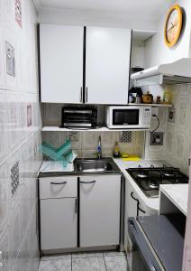 a small kitchen with white cabinets and a sink at Departamento primera línea frente al casino. in Viña del Mar