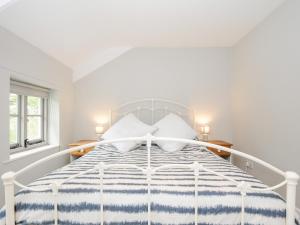 een witte slaapkamer met een bed met een blauwe en witte sprei bij Sherwell Farm Cottage in Callington