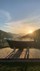 a bath tub sitting on a wooden deck with the sun in the background at Gailerhof Hotel B&B Superior in Monguelfo