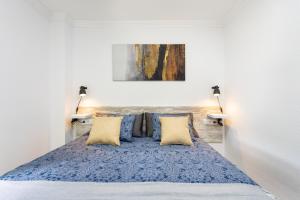 een slaapkamer met een bed met een blauwe deken en kussens bij Tre spaziosi appartamenti a 150m dal lungomare di Las Americas in Arona