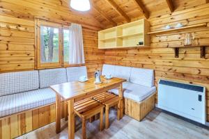 comedor con mesa y bancos en una cabaña de madera en Camping Fontfreda, en Castellar del Riu