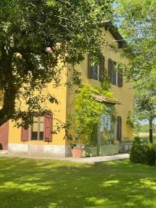 un edificio amarillo con porche y patio en Villa Leopardi, en Vignale