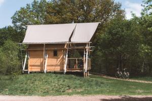 Cabaña de madera con techo de metal y bicicleta en Huttopia de Roos en Stegeren