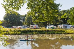 two people on a paddle board on a river with tents at Huttopia de Roos in Stegeren