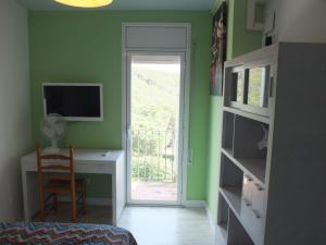 1 dormitorio con paredes verdes, escritorio y ventana en Apartment Platja de Aro con piscina y vistas al mar, en Platja d'Aro