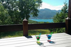 two glasses on a wooden table with a view of a lake at La Palatriere in Le Sauze-du-lac