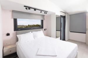 a white bedroom with a large white bed and a window at Blue Avenue in Paliouri