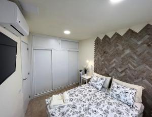een slaapkamer met een bed en een stenen muur bij Sunrise Apartment - Playa del Inglés in Playa del Inglés