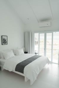 um quarto branco com uma cama grande e uma janela grande em Villa IKIN em Ubud
