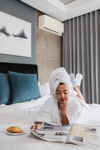 a woman laying on a bed reading a magazine at The Capital Melrose in Johannesburg