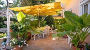 eine Terrasse mit einem gelben Regenschirm sowie Tischen und Pflanzen in der Unterkunft Villa Auguste in Pörtschach am Wörthersee