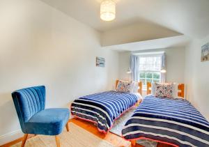 a bedroom with two beds and a blue chair at The Arc in Swanage