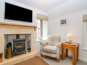 a living room with a fireplace and a chair and a television at The Wee Hideaway in Cupar