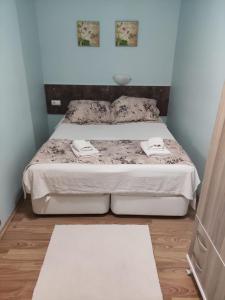 een slaapkamer met een bed met een witte sprei en 2 handdoeken bij LAVİNYA PENSİON in Kuşadası